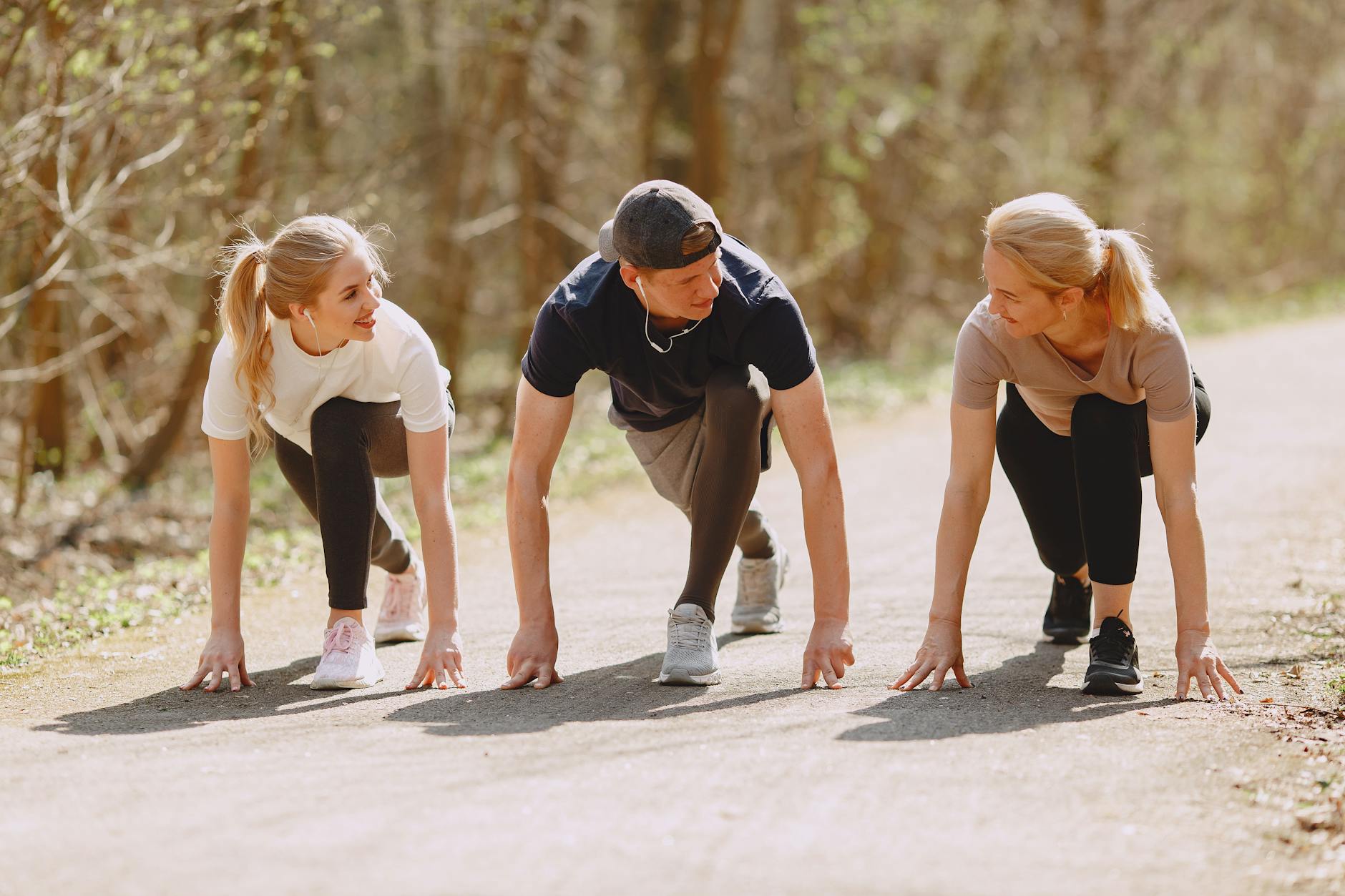 happy sportspeople of different ages preparing to run in forest